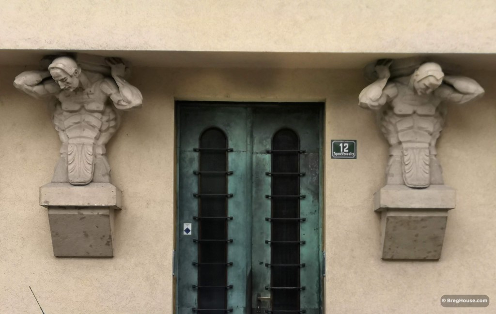 Art decor door in Ljubljana, Slovenia, flanked by two sculptures.