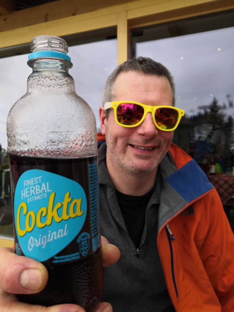 A man holds a bottle of Slovenian soft drink - Cockta
